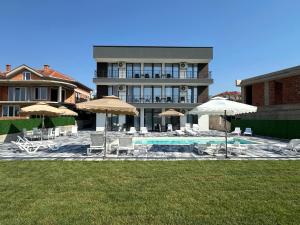 a building with a pool and chairs and umbrellas at Lakeview Apartments in Veles