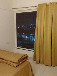 a bedroom with a window with a view of a city at MaEra's Den in Hinjewadi