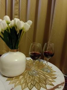 two glasses of wine and a vase of flowers on a table at MaEra's Den in Hinjewadi