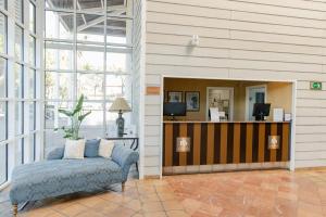 a room with a couch and a desk with a television at Hotel Nuevo Portil Golf in El Rompido