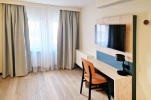 a room with a desk with a television and a chair at Hotel Boulevard in Stuttgart