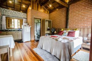 a bedroom with a bed and a brick wall at Chalés Aguas Serenas in Santo Antônio do Pinhal
