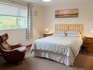 a bedroom with a bed and a chair and a window at Uk47550 - Cairnsmore Cottage in Newton Stewart