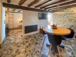 a dining room with a table and chairs and a stone wall at Cal Serni in Calbinyà