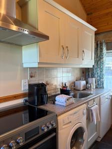a kitchen with a sink and a washing machine at Derryvree Farm Cottage in Maguires Bridge +14 photos