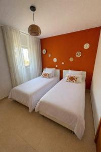 two beds in a room with orange walls at Apartamento Paradise beach in Prainha +7 photos