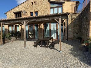a picnic table and bench in front of a building at Case vacanza "LA FORNACE" in Vagliagli