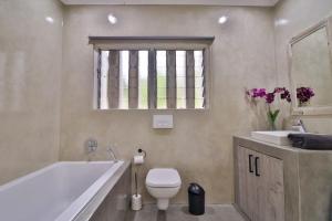 a bathroom with a tub and a toilet and a sink at Panorama View Pool House Steiltes I in Nelspruit +9 photos