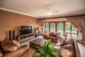 a living room with leather furniture and a flat screen tv at Panorama View Pool House Steiltes I in Nelspruit
