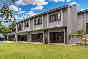 a large white building with windows and a yard at Panorama View Pool House Steiltes I in Nelspruit