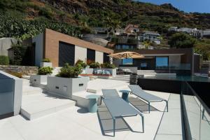 an outdoor patio with tables and chairs on a house at Villa Anjos - Luxury Villa with Infinity Pool & Ocean View in Canhas