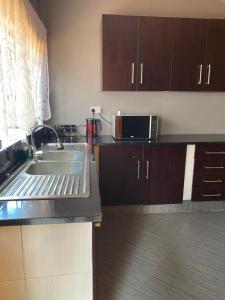 a kitchen with a sink and a microwave at Ramachi apartments in Livingstone