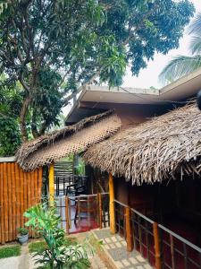 a house with a thatched roof and a table at Tuskers edge Retreat in Udawalawe +16 photos