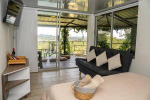 a room with a bed and a couch and a balcony at Rocks Glamping - Guatapé, El Peñol in El Peñol