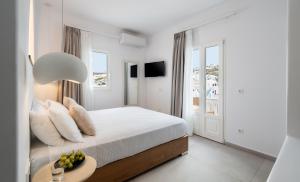 a white bedroom with a bed and a table with a bowl of fruit at Galation in Mikonos