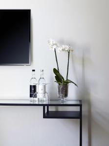 a glass table with a vase of flowers and a tv at Hotel Trabener Hof in Traben-Trarbach +23 photos