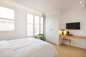 a white bedroom with a bed and a desk at Babel Community Hôtel - Montpellier centre in Montpellier +31 photos