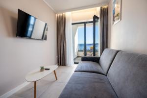 a living room with a couch and a tv at Wind Rose Bura-beachfront in Igrane
