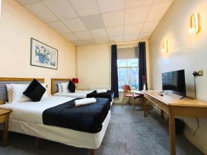 a hotel room with two beds and a desk at Throstles Nest Hotel in Liverpool