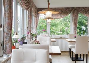 a dining room with white chairs and large windows at Haus zur Heimat in Cuxhaven