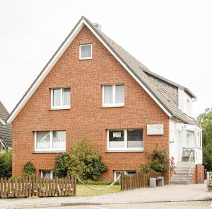 a red brick house with a wooden fence at Haus zur Heimat in Cuxhaven