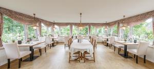 a dining room with tables and chairs and windows at Haus zur Heimat in Cuxhaven