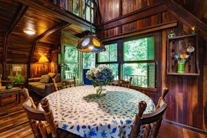 a dining room with a table with a vase of flowers on it at Rosa Chalé do Vô Walter in Gramado