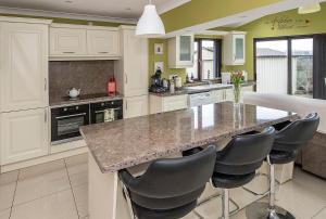 a kitchen with white cabinets and a island with bar stools at Sleepy Rock in Dungarvan