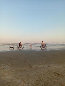 a group of people riding bikes and a dog on the beach at Cabanas Sol e Lua in Imbé
