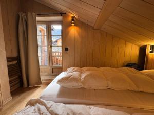 a large bed in a room with a window at Cosy duplex close to Verbier in Bruson