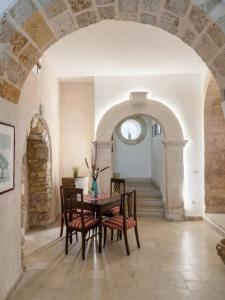 a dining room with an archway and a table and chairs at Ortigia Mastrarua rooms in Syracuse