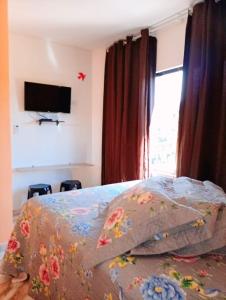 a bedroom with a bed and a tv on the wall at Pousada Opção I in Triunfo