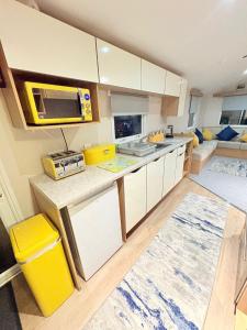 a kitchen with white cabinets and a yellow microwave at The Vacation Lyons Winkups Towyn in Kinmel Bay