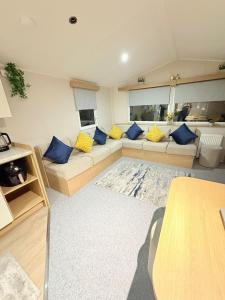 a living room with a couch and blue pillows at The Vacation Lyons Winkups Towyn in Kinmel Bay