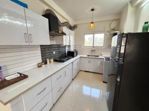 a kitchen with white cabinets and a black refrigerator at The Huddle - Dawn in Dehradun