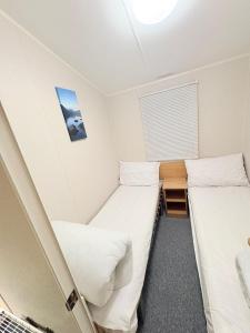 two beds in a small room with a window at The Vacation Lyons Winkups Towyn in Kinmel Bay +6 photos