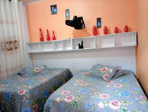 a bedroom with two beds and red vases on shelves at Pousada Opção I in Triunfo +15 photos