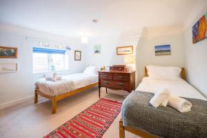a bedroom with two beds and a dresser and a window at The Old Bakery, Wrentham in Wrentham