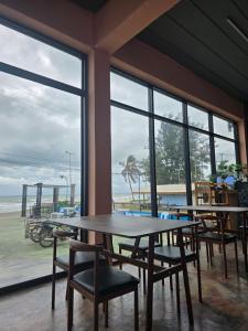 a table and chairs in a room with windows at โรงแรมเลทุ่งแล่น 109 in Ban Phru Ching (1)