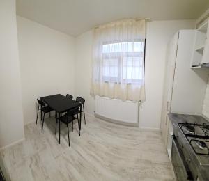 a small white kitchen with a table and a window at Garsonieră O&M in Craiova