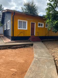 a small yellow house with a door in a yard at Ramachi apartments in Livingstone