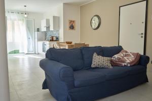 a blue couch in a living room with a clock on the wall at La Casa di Zefiro in Santa Flavia