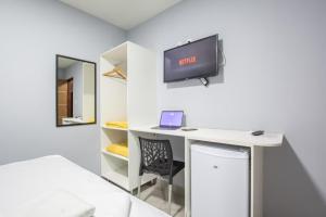 a room with a bed and a desk with a monitor at Pousada Recanto do Sol BF in Baía Formosa
