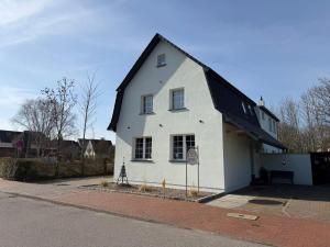 a white house with a black roof on a street at Gästehaus Alexandra in Cuxhaven +3 photos