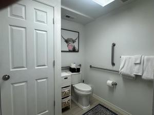 a bathroom with a toilet and a picture of a cow at Contemporary Dual-Unit 2BR Downtown Branson - Free Tickets Included - LOFT in Branson +22 photos