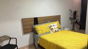 a bedroom with a bed with a yellow comforter at Casa Homero 23 in Morelia