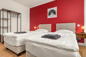 two beds in a room with a red wall at HOMEBASE - Design Lofts am Schloss in Montabaur +44 photos