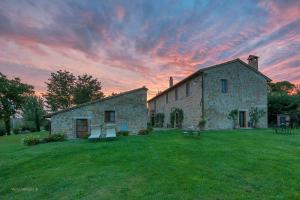 an old stone building in a field with a sunset at Podere Lamone a Monticchiello in Monticchiello