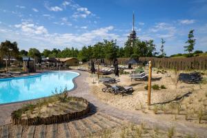ein Swimmingpool mit Liegestühlen und Sonnenschirmen in einem Ferienresort in der Unterkunft Waterstate Wellness hotel Goes in Goes