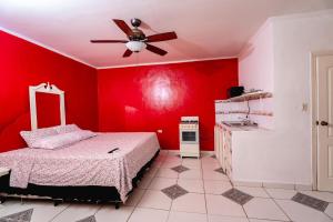 a red bedroom with a bed and a ceiling fan at Hotel&Hostal Trinidad in La Ceiba
